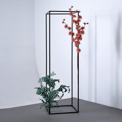Decorative plant stand with pink flowers and greenery against a plain background