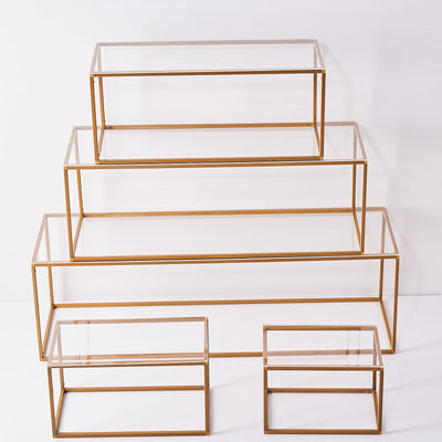 Gold-framed glass display stands in varying sizes arranged in a tiered formation.