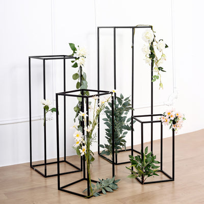 Decorative black metal display stands with artificial flowers.