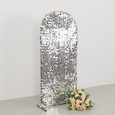 Decorative mirror with a silver mosaic design and floral arrangement in front.