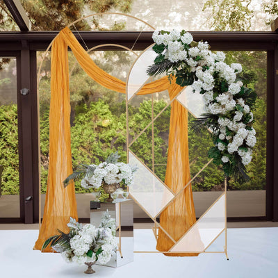 Wedding floral arch with orange drapery and white flowers in a scenic outdoor setting.