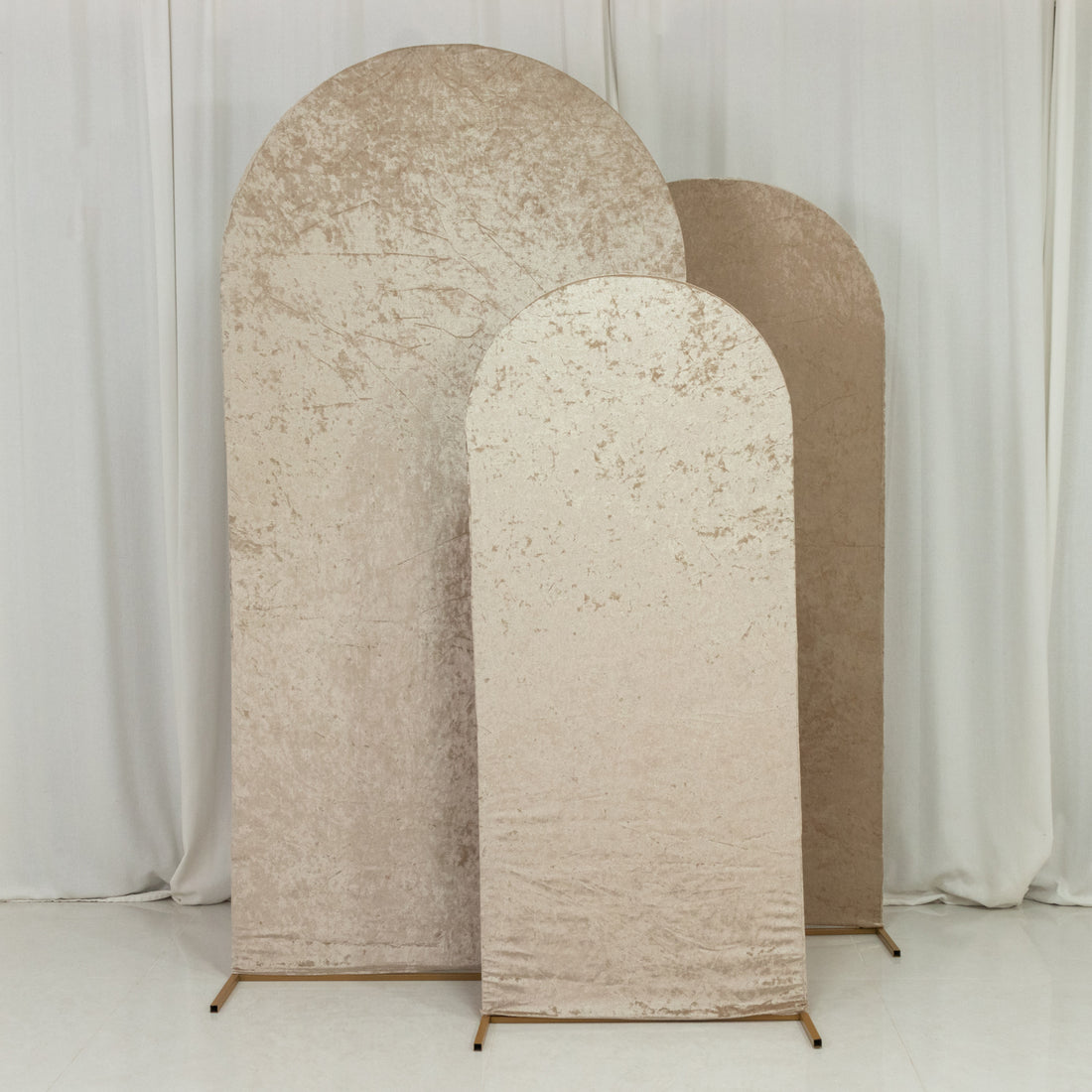 Three textured fabric backdrops in beige tones, varying in height and shape.