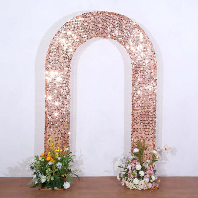 Rose gold sequin arch with floral arrangements at the base.