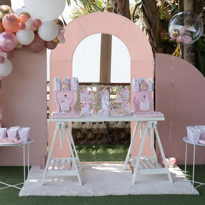 Pastel-themed dessert table setup with balloons and decorations.