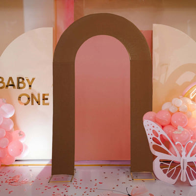 Brown arch decoration for baby event backdrop with balloons and butterfly accents.