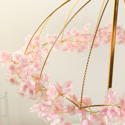 Pink floral chandelier with gold accents against a plain backdrop.