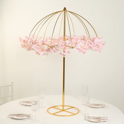 Gold floral umbrella centerpiece with pink blossoms on a table setting.
