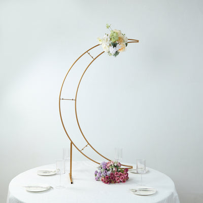 Gold floral arch with white and pastel flowers on a table setting.
