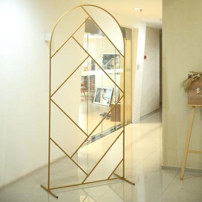 Gold arch mirror stand with geometric design in a modern interior setting.