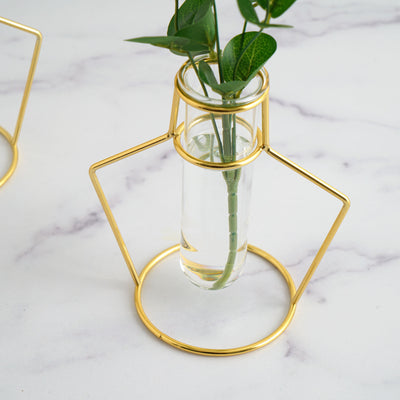 Gold geometric vase holder with a glass tube for fresh flowers.
