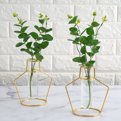 Gold wire vases with greenery on a marble surface.