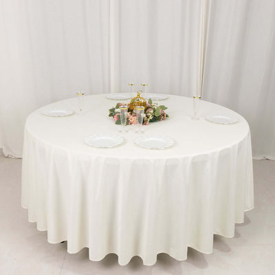 Elegant round dining table set with white tablecloth and decorative centerpiece.