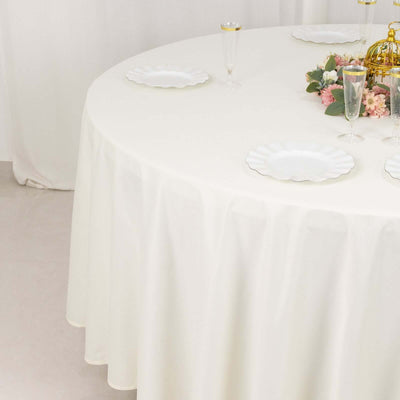 Elegant round table set with white plates and floral centerpiece.
