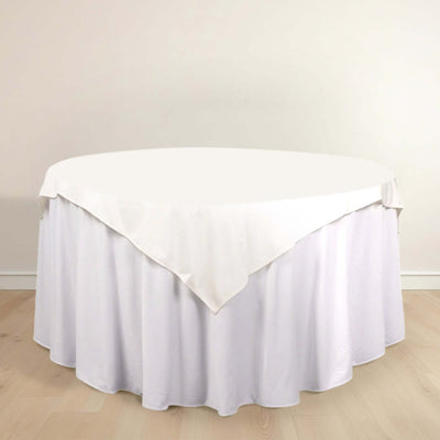 Round table with white tablecloth on a wooden floor.