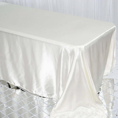 Elegant ivory satin tablecloth draping a table in a studio setting.