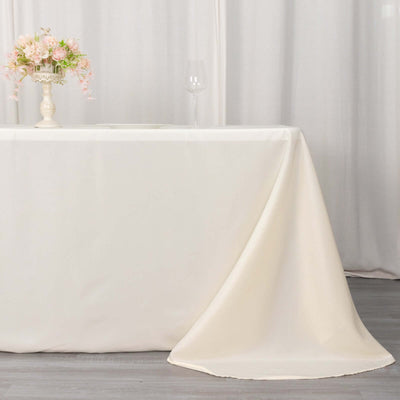 Elegant cream tablecloth draping over a table with floral centerpiece and glass.