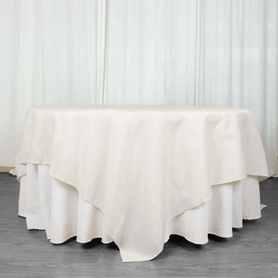 Round cream tablecloth draped over a table in a simple setting.