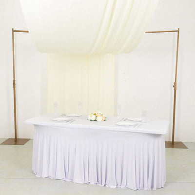 Elegant wedding table setup with draped fabric and floral centerpiece.