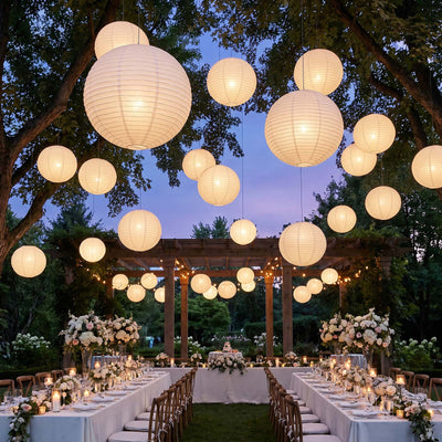 Outdoor wedding reception with hanging lanterns, floral tables, and twilight garden setting