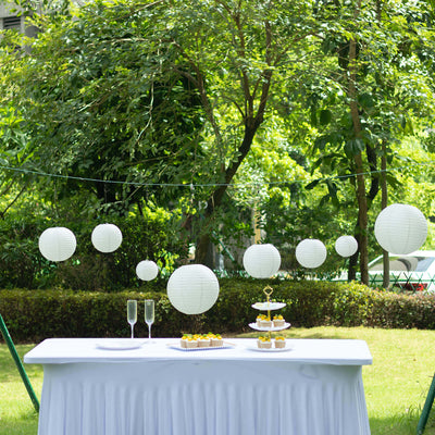 Outdoor event table setup with white lanterns and dessert display.