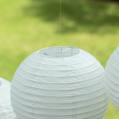 White paper lantern hanging outdoors, showcasing its round shape and wire frame.