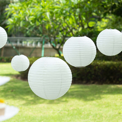 White paper lanterns hanging outdoors in a garden setting.