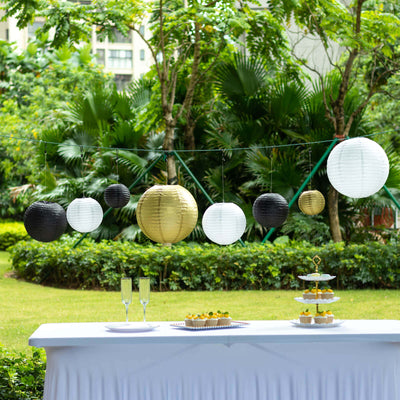 Decorative paper lanterns in black, white, and gold at an outdoor party setup.