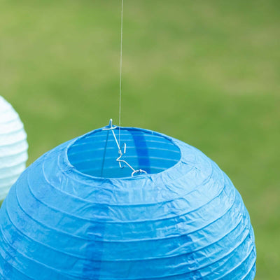 Blue paper lantern hanging outdoors against a green background.