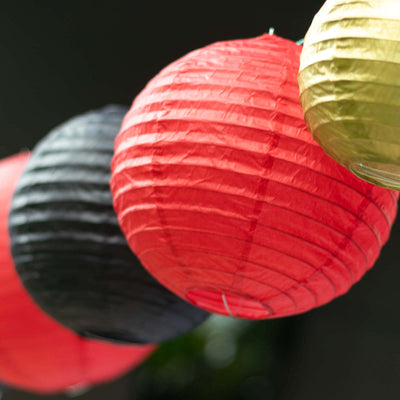 Colorful paper lanterns in red, black, and gold hanging together.