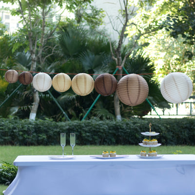 Decorative paper lanterns hanging at an outdoor event with a dessert table.