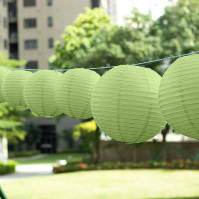 Green paper lanterns hanging outdoors in a garden setting.