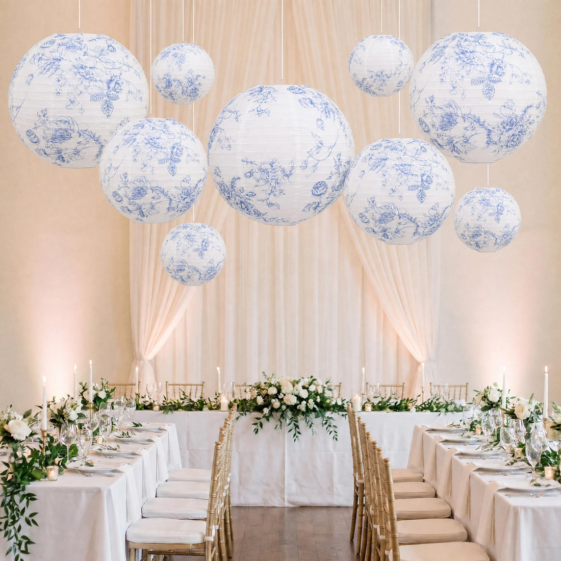 Elegant wedding reception with floral lanterns, white drapery, and gold chairs