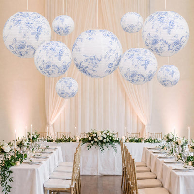 Elegant wedding reception with floral lanterns, white drapery, and gold chairs
