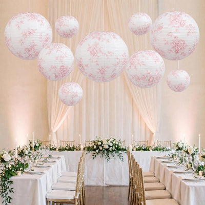 Elegant wedding reception with floral lanterns, white table settings, and gold chairs