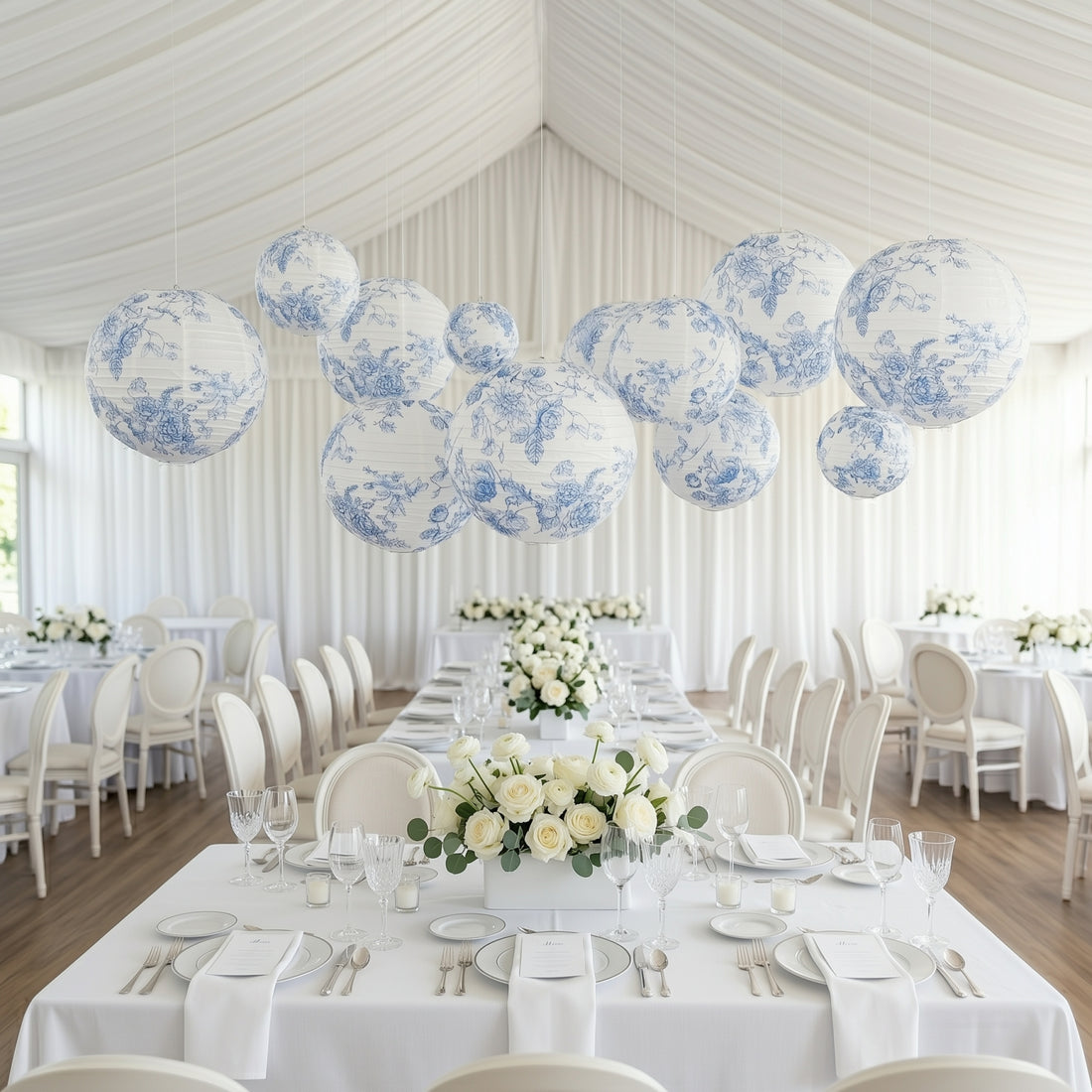 Blue and white floral paper lanterns hanging over an elegant dining setup.