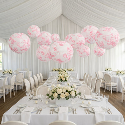Decorative pink floral lanterns suspended over an elegant dining setup.