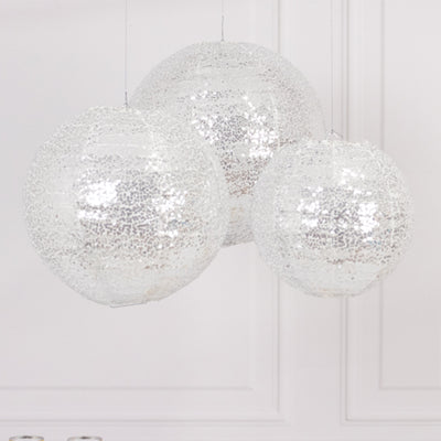 Three shimmering silver globe pendant lights hanging in a bright interior.