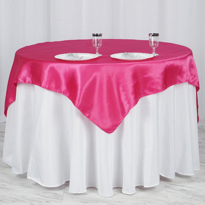Round table set with pink satin tablecloth and white underlayer. Elegant dining setup.