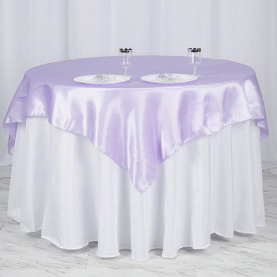 Round table with lavender satin tablecloth and two plates on a white table skirt.