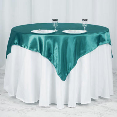 Teal satin tablecloth draped over a round table with white skirt