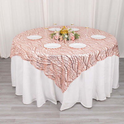 Round table with pink and white patterned tablecloth and floral centerpiece.