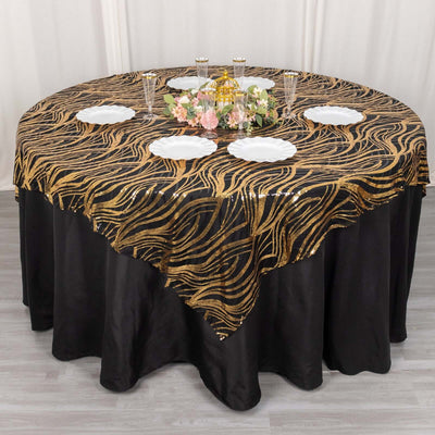 Gold wave patterned tablecloth on a round table with plates and floral centerpiece.