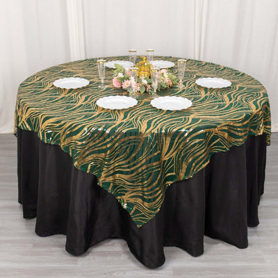 Elegant green and gold patterned tablecloth on a round table with dishes and decor.