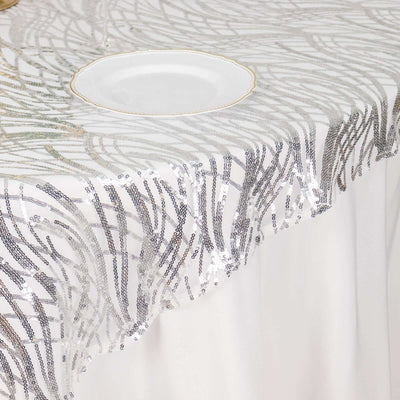 Silver sequin tablecloth with intricate design on a white table.