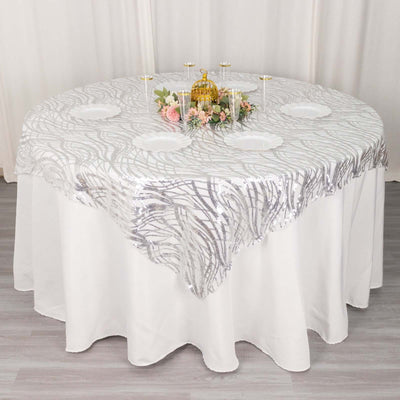 Round table with elegant silver sequin tablecloth and floral centerpiece.