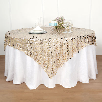 Gold sequin table cover on a round white table with floral centerpiece.
