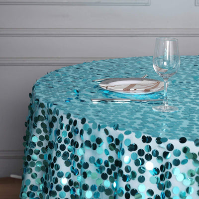 Turquoise sequin tablecloth with a plate and glass on a round table.