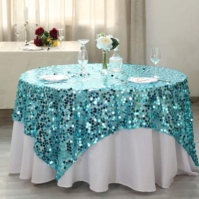 Turquoise sequin tablecloth draped over a round table with elegant decor.