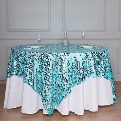 Teal and silver sequin tablecloth draped over a round table with glasses.