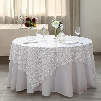 White sequined tablecloth draped over a round table in an elegant setting.